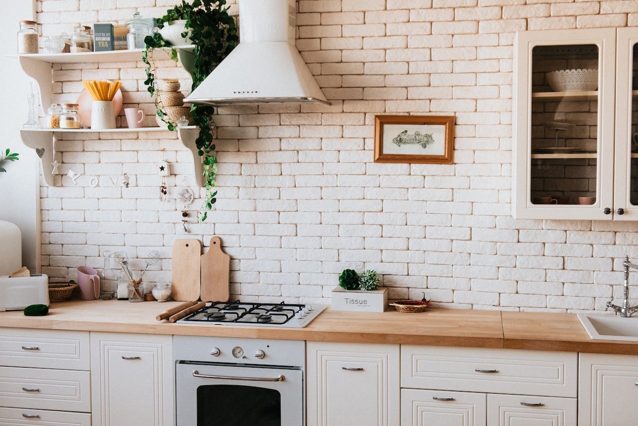 Modern home kitchen interior with a clean design, featuring an air purifier on the countertop, white brick backsplash, and natural wood cabinets, creating a healthy cooking environment