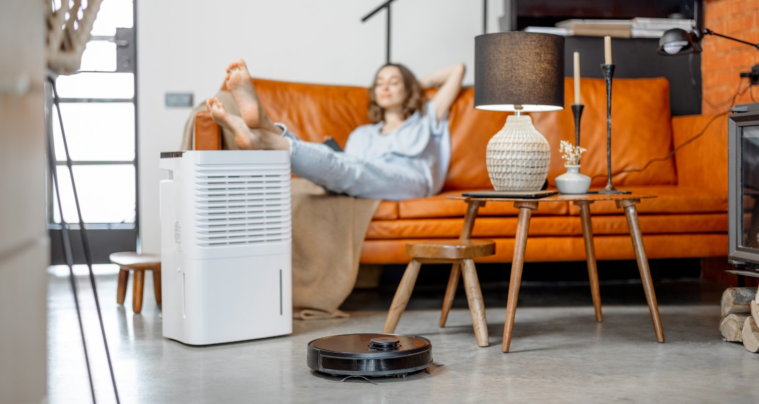 Woman lying back on her orange couch in her home with her feet propped up on an air purifier