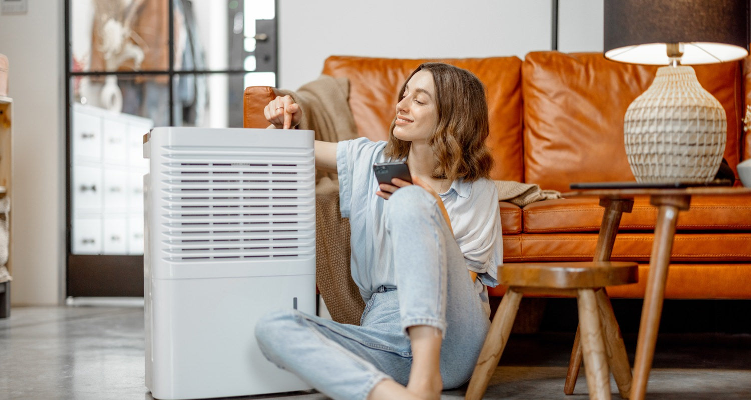 Woman sitting next to an air purifier in her family room and turning it on