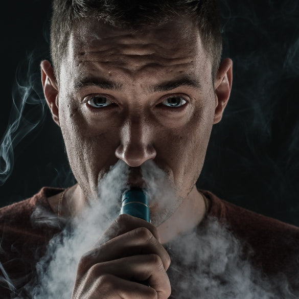 Man smoking vape pen with smoke surrounding him