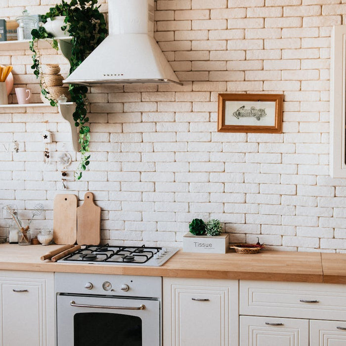 Modern home kitchen interior with a clean design, featuring an air purifier on the countertop, white brick backsplash, and natural wood cabinets, creating a healthy cooking environment