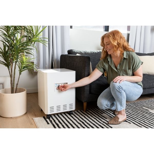 EnviroKlenz Air System Plus in living room with woman turning on the machine